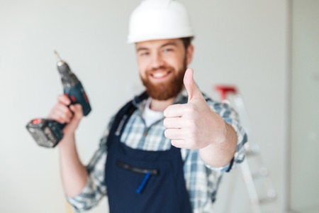 Close up of smiling man builder showing thumb up isolatedの写真素材