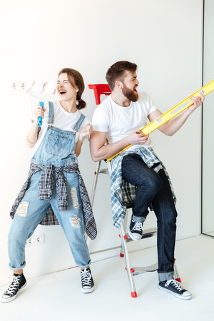 Full length portrait of a happy joyful couple holding work tools and having fun while having a break in repairing their houseの写真素材