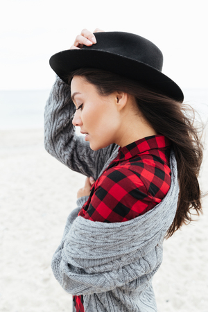 Woman wrapping in warm jacket while walking near seaの写真素材