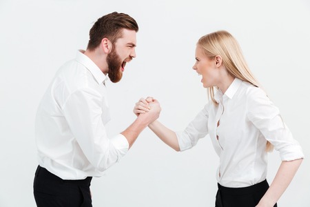 Image of screaming colleagues business team standing over white background isolated. Looking at each other and shaking hands.の写真素材