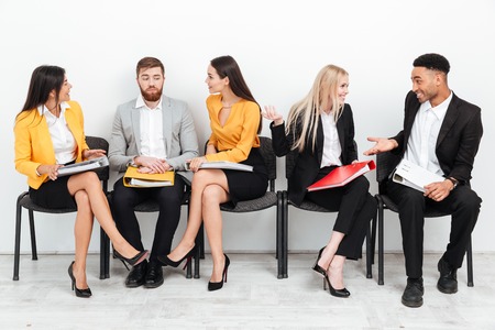 Photo of a group of colleagues sitting in office talking with each other. Looking aside.の写真素材