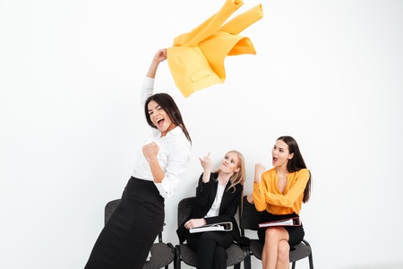 Image of angry women looking at happy lady colleague looking at camera make winner gesture.の写真素材