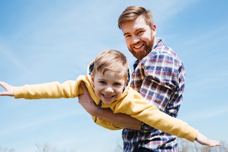 Close up of a young smiling father and his little son playing together in a city parkの写真素材