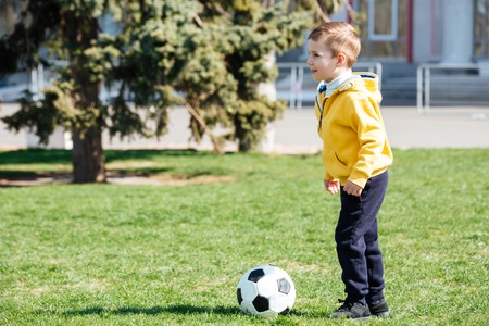 Cute little boy playing football in park outdoorsの写真素材