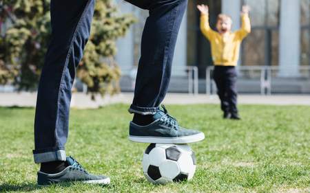 Cropped image of a father playing football with his little son outdoorsの写真素材