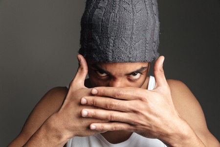 Image of young african man isolated over grey background. Looking at camera covering face with hands.の写真素材