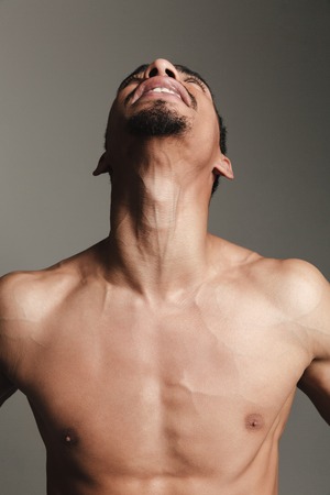 Picture of young laughing african man isolated over grey background. Looking aside.の写真素材