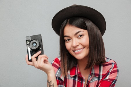 Picture of funny young asian woman isolated over grey wall holding camera.の写真素材