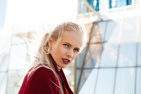 Image of young beautiful serious caucasian woman walking outdoors. Looking at camera.
