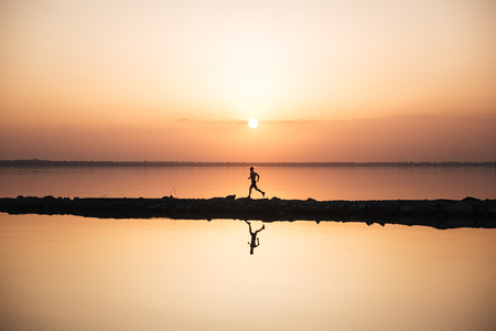 Image of handsome young sportsman running at the beach. Looking aside.の写真素材
