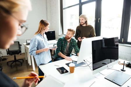 Image of young concentrated colleagues in office using computer. Looking aside.