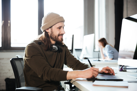 Picture of young handsome man work in office using computer. Looking aside.の写真素材