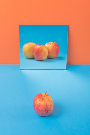 Image of apple on blue table isolated over orange backgroundの写真素材