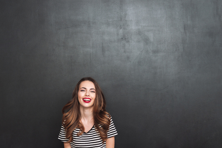 Laughing woman posing in studio and looking at the camera over black backgroundの写真素材