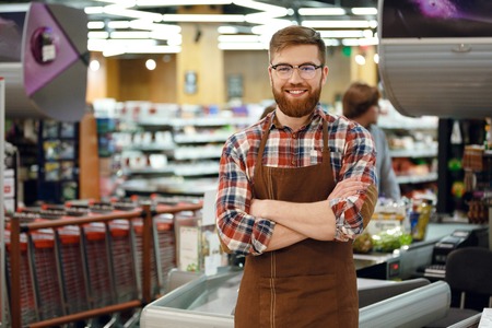 Picture of cashier man on workspace in supermarket shop. Looking at camera.の写真素材