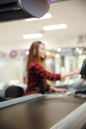 Blurred picture of cashier lady on workspace in supermarket shop. Focus on desk.の写真素材