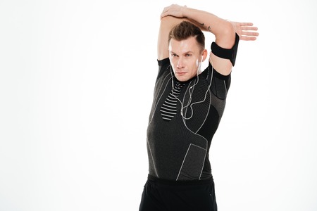 Portrait of a young handsome sportsman stretching hands before workout isolated over white backgroundの写真素材