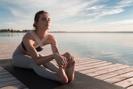 Picture of young sports woman at the beach make stretching exercises.