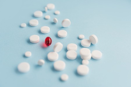 Close up of white tablets with one red capsule isolatedの写真素材