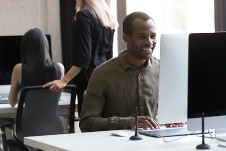 Smiling african american businessman working on his computer at the officeの写真素材