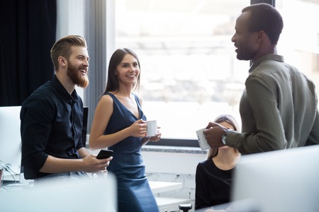 Young afro american man having a conversation with two of his colleagues in an office