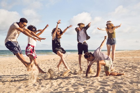 Happy young people jumping on the beach and having fun