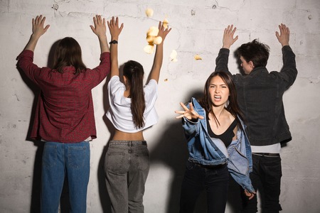 Image of young angry hipsters loving couples standing over gray background. Woman scatter bread...