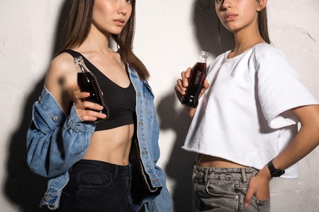 Cropped photo of young hipster friends women standing over gray background drinking aerated water.の写真素材