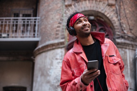 Portrait of a smiling afro american man listening to music outdoors on a street