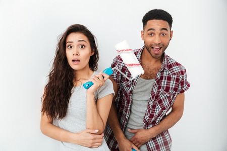 Suprised cute woman with glad african man looking cameraの写真素材