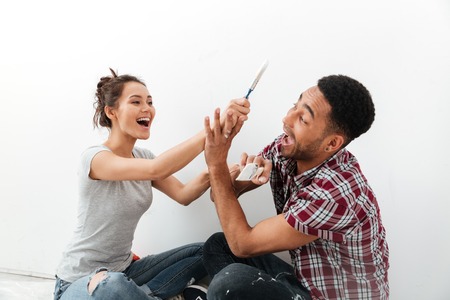 Image of happy young loving couple sitting on floor in new flat makes repair. Looking aside.の写真素材