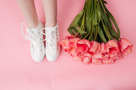 Cropped image of bouquet of flowers and legs of woman over pink backgroundの写真素材