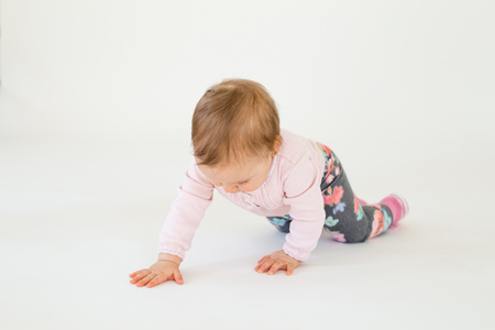 Image of cute baby girl on floor isolated over white background. Looking aside.の写真素材