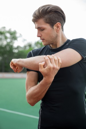 Image of young male athlete make stretching exercises outdoors. Looking aside.の写真素材
