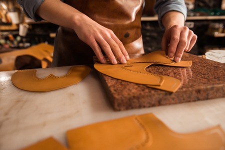 Close up of a male cobbler working with leather textile at his workplace