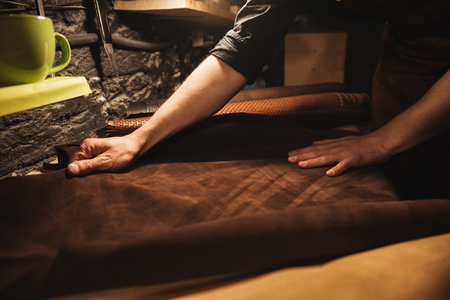 Cropped image of young man shoemaker at footwear workshop.の写真素材