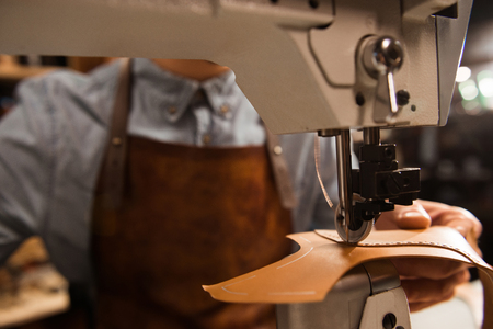 Close up of a cobbler using sewing machine at a workshop