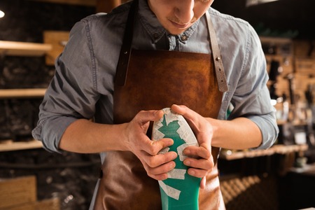 Cropped image of a male cobbler modeling design for a shoe at his workshop