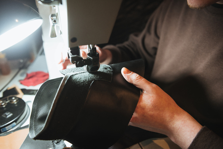 Cropped photo of young man shoemaker at footwear workshop.