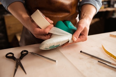 Close up of a cobbler modeling mens shoe at his workshopの写真素材