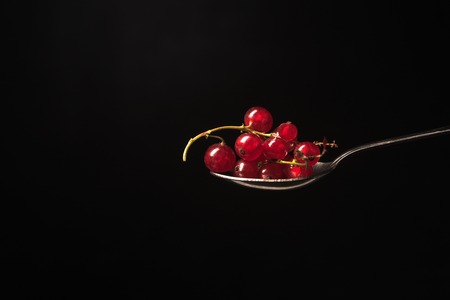 Spoon with currant isolated over black background.の写真素材