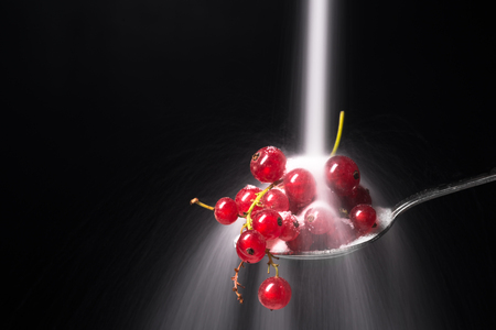 Sugar pours on the currant with blueberries isolated over black background.の写真素材