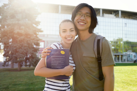 Picture of young cheerful students standing outdoors. Looking camera.の写真素材