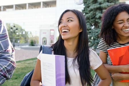 Image of young cheerful student asian woman standing outdoors. Looking aside.の写真素材