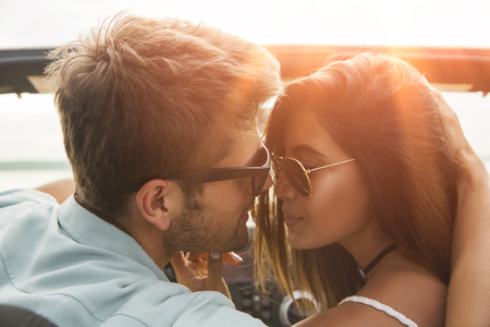 Close up of a smiling young couple kissing while sitting in a carの写真素材