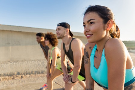 Close up of a young sporty woman doing sports with a group of friends outdoorsの写真素材