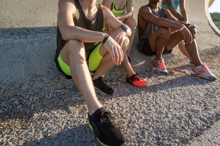 Cropped image of young people in sportswear sitting outdoorsの写真素材