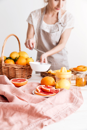 Cropped image of woman standing indoors and squeezes out juice of a citruses.の写真素材