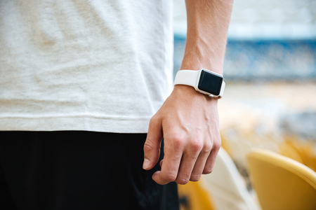 Cropped photo of young sportsman's hand with watch at the stadium outdoors.の写真素材
