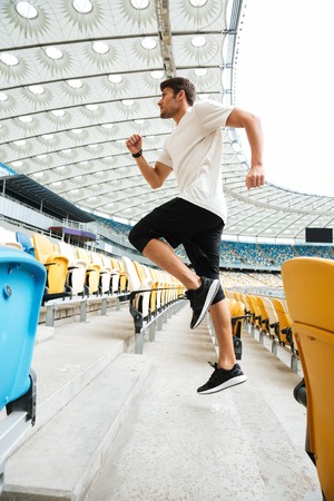 Side view of a sporty athlete man running upstairs at the stadiumの写真素材